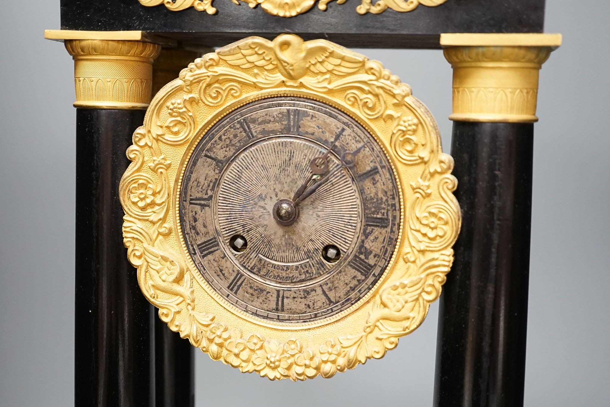 A 19th century ebonised portico mantel clock with brass mounts, 46cms high.